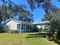 House exterior showcasing a light blue vinyl-sided home with a covered porch and lush landscaping at 5062 El Destino Dr, Leesburg, FL 34748