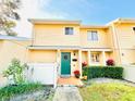 Cute yellow two-story house with green door, landscaping, and white fence at 2254 Ohara Ct # 1055, Orlando, FL 32812