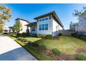 Modern single-story home with gray and white exterior, landscaping, and paved walkway at 8664 Dubochet St, Orlando, FL 32827