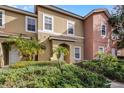 Two-story townhome with tan and peach exterior, and lush landscaping at 3083 Yellow Lantana Ln, Kissimmee, FL 34747
