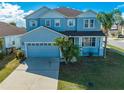 Front exterior view of a two-story home with attached two-car garage and palm trees at 1079 Berkeley Dr, Kissimmee, FL 34744
