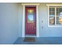 Close-up of the front door. It is a dark red color with decorative glass panels at 1079 Berkeley Dr, Kissimmee, FL 34744