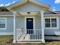 Front entrance with a white railing and blue door at 4423 Reaves Rd, Kissimmee, FL 34746