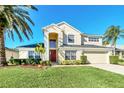 Two-story house with beige exterior, red front door, and palm trees at 1020 Golf Course Pkwy, Davenport, FL 33837