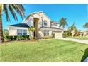 Two-story house with beige exterior, lush landscaping, and palm trees at 1020 Golf Course Pkwy, Davenport, FL 33837
