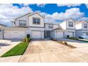 Inviting two-story townhome with a white and gray exterior, attached garage, and lush landscaping at 3896 Grassland Dr, Orlando, FL 32824