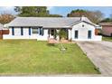 Single-story home with a gray roof, white exterior, blue shutters, and a lush green lawn at 1375 Springfield St, Kissimmee, FL 34744