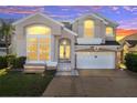 Two-story house with a large front yard, a two-car garage, and a brick driveway at sunset at 2430 Berkshire Ct, Kissimmee, FL 34746
