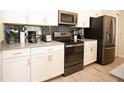 Stylish kitchen with white cabinets, dark appliances, and a gray tile backsplash at 890 Pebble Beach Dr, Davenport, FL 33896