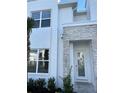 Close-up of a modern home's entrance with white door, gray stone accents, and landscaping at 1396 Peaceful Nature Way # 1396, Clermont, FL 34714