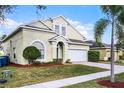 Tan two-story house with a well-manicured lawn and a two-car garage at 242 Cadiz Loop, Davenport, FL 33837