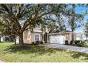 Two-story house with tan exterior, white garage door, and large tree to the left at 673 Copeland Dr, Haines City, FL 33844
