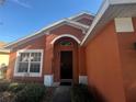 Front door and entryway of a one-story house with orange exterior at 922 Sandy Ridge Drive Dr, Davenport, FL 33896