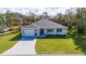 Single story house with gray roof and white walls, landscaped yard and driveway at 2828 Sequoyah Dr, Haines City, FL 33844