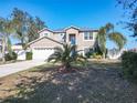 Two-story house with a neutral exterior, a two-car garage, and palm trees at 513 Big Black Way, Kissimmee, FL 34759