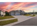 Two-story house with a two-car garage, driveway, and beautiful sunset at 2937 Hooded Crane Cv, Harmony, FL 34773