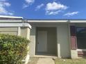 Front entrance of a light green house with a white door and dark red shutters at 34 Pine Island Cir, Kissimmee, FL 34743