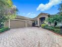 House with paver driveway, two-car garage, and manicured landscaping at 542 Viterra Ct, Kissimmee, FL 34759