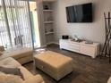 Living room features wood-look floors and large TV at 8939 Latrec Ave # 1211, Orlando, FL 32819