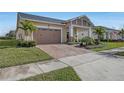 Tan house with palm trees, a two-car garage, and a brick driveway at 5043 Vantage Ct, St Cloud, FL 34772