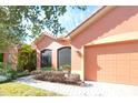 Orange stucco home with two car garage and well manicured landscaping at 521 Milano Rd, Kissimmee, FL 34759