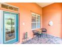 Inviting front porch with teal door, brick flooring and small sitting area at 521 Milano Rd, Kissimmee, FL 34759