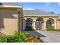 Tan house with arched entryway, three-car garage, and manicured landscaping at 1280 Osprey Landing Dr, Lakeland, FL 33813