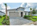 One-story house with a gray and beige exterior, paved driveway, and tropical landscaping at 128 Mosaic Blvd, Daytona Beach, FL 32124