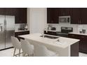 Modern kitchen boasts dark cabinetry, an island, and stainless steel appliances at 1153 Deepwater Cir, Eagle Lake, FL 33839