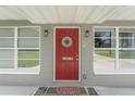 Red front door with a seashell wreath and stone flooring at 1075 8Th Nw St, Winter Haven, FL 33881