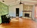 Living room with stone fireplace and leafy wallpaper accent wall at 13659 Sw 115Th Pl, Dunnellon, FL 34432