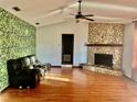 Living room with stone fireplace and leafy wallpaper accent wall at 13659 Sw 115Th Pl, Dunnellon, FL 34432