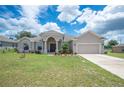 Tan one-story house with a three-car garage and manicured lawn at 4046 Dinner Lake Way, Lake Wales, FL 33859