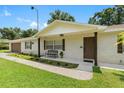 White brick home with brown accents, a covered porch, and a manicured lawn at 4314 Ridge Rd, Lakeland, FL 33811