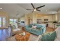 Open-concept living room and kitchen with teal sofa and wicker chairs at 7031 Red Grange Boulevard Ave, Indian Lake Estates, FL 33855