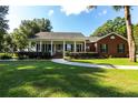 Brick house with a large front porch and landscaped yard at 6010 Se 99Th Pl, Belleview, FL 34420