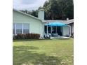 Backyard patio with two blue umbrellas, white chairs and a small dog at 10742 W Beach Pkwy, Lake Wales, FL 33898
