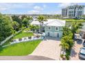 Luxury waterfront home with a large yard, palm trees, and a paved driveway at 444 Quay Assisi, New Smyrna Beach, FL 32169