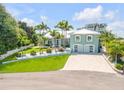 Luxury waterfront home with a large yard, palm trees, and a paved driveway at 444 Quay Assisi, New Smyrna Beach, FL 32169