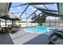 Relaxing screened pool area with patio furniture and a large umbrella at 105 Hainesport Dr, Lake Alfred, FL 33850
