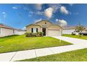 Tan one-story house with a two-car garage and landscaped yard at 6048 Forest Ridge Ln, Winter Haven, FL 33881