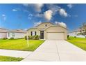 Tan one-story house with a two-car garage and landscaped yard at 6048 Forest Ridge Ln, Winter Haven, FL 33881