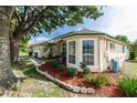House exterior with a large tree, manicured landscaping, and a bay window at 107 Needlewood Loop, Debary, FL 32713