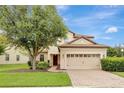 Two-story house with tan exterior, tile roof and three-car garage at 9151 Wedge Dr, Davenport, FL 33896