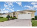 One-story house with a red door and two-car garage at 24429 Madewood Ave, Leesburg, FL 34748