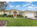 One-story house with a red door and two-car garage at 24429 Madewood Ave, Leesburg, FL 34748