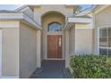 The front door is a brown wood door with a glass insert and arched window above at 2729 Wilshire Rd, Clermont, FL 34714