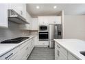 Modern white kitchen with stainless steel appliances and quartz countertops at 7737 Somersworth Dr, Kissimmee, FL 34747