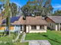 Tan house with brown roof, solar panels, and a small front yard at 1057 Old South Dr, Lakeland, FL 33811
