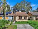 Tan house with brown roof, solar panels, and a small front yard at 1057 Old South Dr, Lakeland, FL 33811